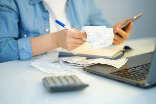 Frau mit einem Stift, hält Rechnungen um Ausgaben abzurechnen