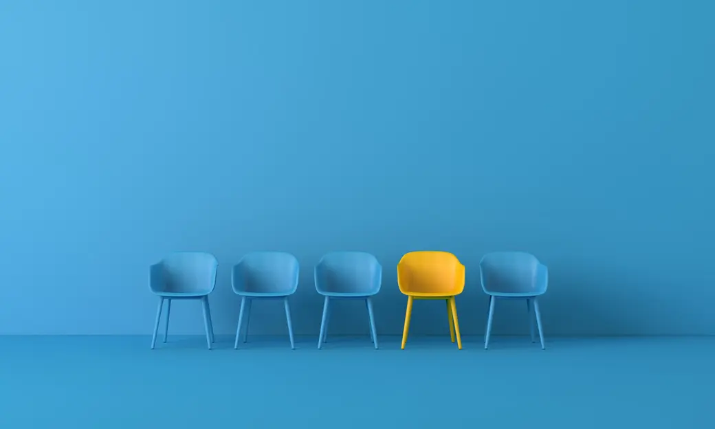 Vier blaue und ein gelber Stuhl vor blauem Hintergrund.